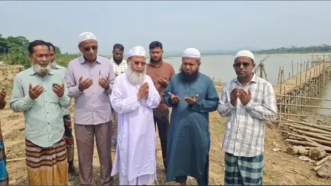 সোমেশ্বরী নদীর পাড়ে দোয়ায় দাঁড়ানো মানুষ, পাশে বাঁশের অস্থায়ী সেতু